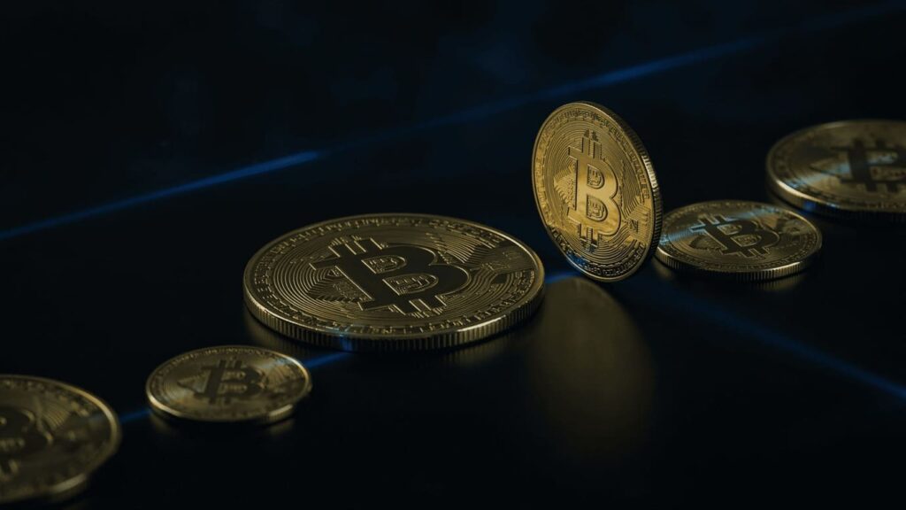 bitcoin gold coins on dark reflective surface with blue light streaks, dramatic financial atmosphere