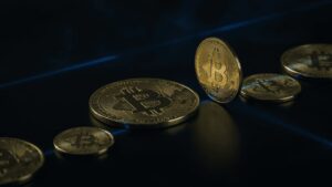 bitcoin gold coins on dark reflective surface with blue light streaks, dramatic financial atmosphere