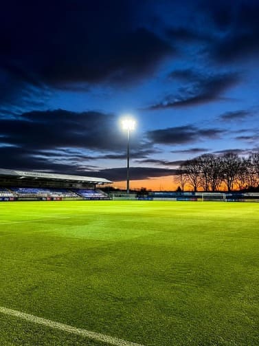 stadium_floodlights_illuminating_a_football_pitch_at_dusk